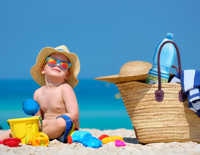 bambino in spiaggia con cappello e bottiglia acqua fontenoce