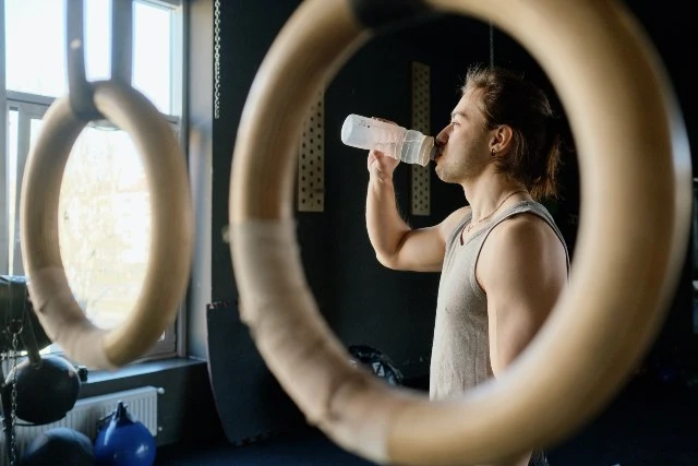 atleta muscoloso beve acqua durante allenamento